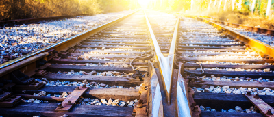 two train tracks with the sun in background