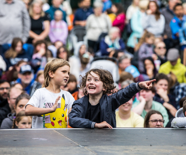 A crowd shot from SIRF 2023 showing two children at the front enjoying the performance with one pointing excitedly at something.