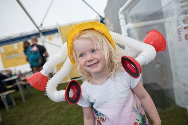 Little girl with a safety hat on that has white pipes stuck to it to create a new invention.